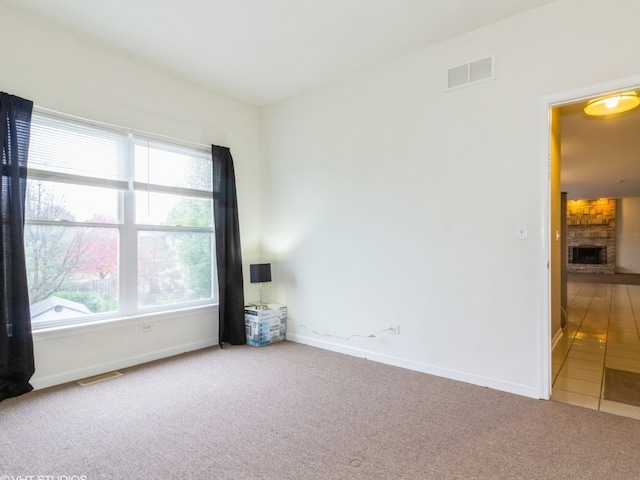 carpeted empty room with a fireplace