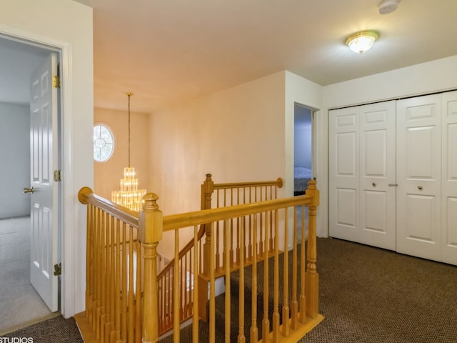 corridor featuring a notable chandelier and dark colored carpet