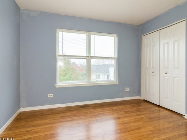 unfurnished bedroom featuring a closet, light hardwood / wood-style flooring, and multiple windows