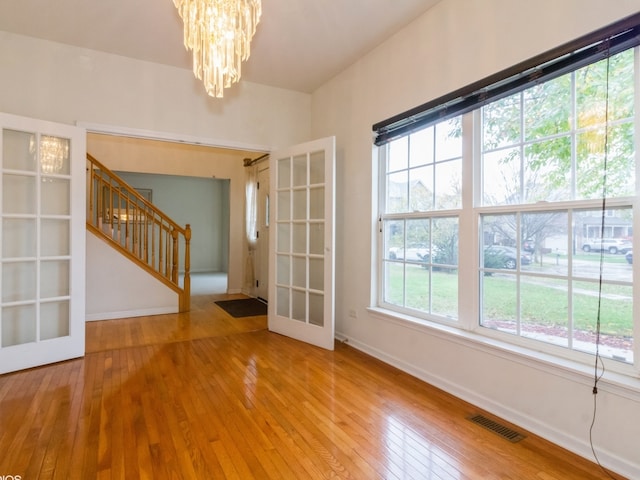 spare room featuring a chandelier, french doors, and hardwood / wood-style flooring