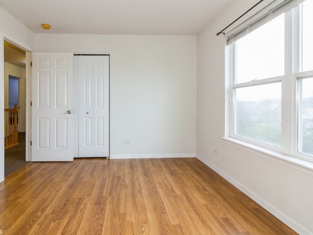 unfurnished bedroom with light wood-type flooring and a closet