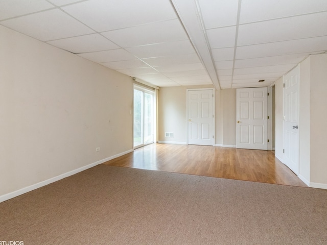 empty room with a paneled ceiling and light hardwood / wood-style floors