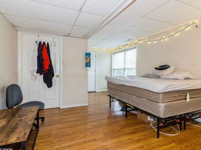 bedroom featuring a paneled ceiling, a closet, and wood-type flooring