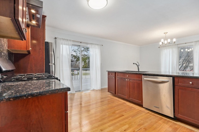 kitchen featuring appliances with stainless steel finishes, dark stone counters, sink, decorative light fixtures, and an inviting chandelier