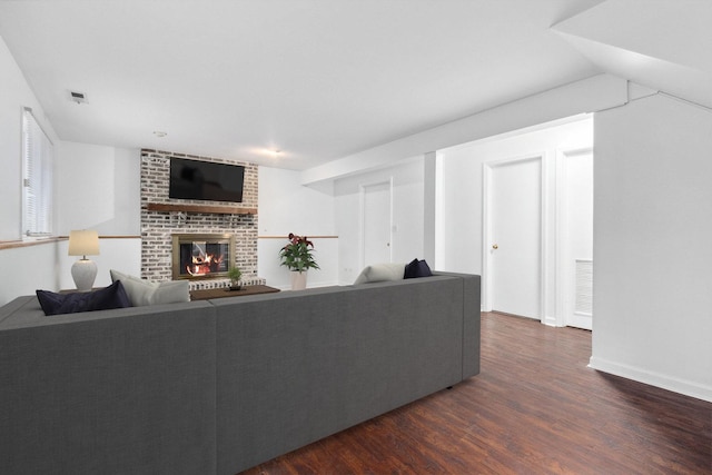 living room featuring dark hardwood / wood-style flooring and a brick fireplace