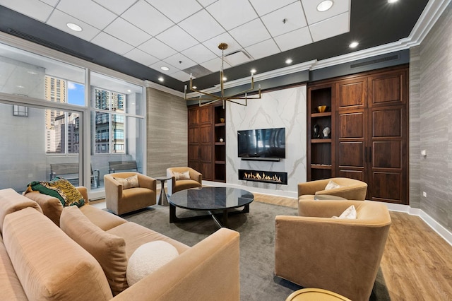 living room featuring crown molding, hardwood / wood-style flooring, built in features, and a premium fireplace