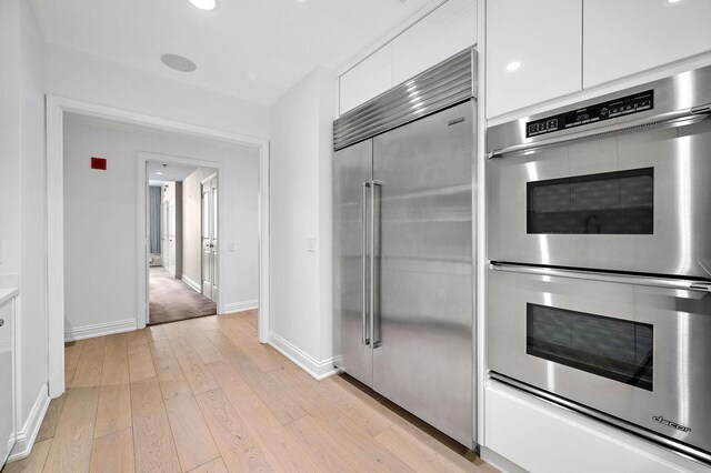 kitchen featuring stainless steel appliances, white cabinets, and light hardwood / wood-style flooring