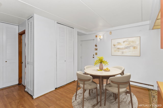 dining space with hardwood / wood-style floors and a baseboard heating unit