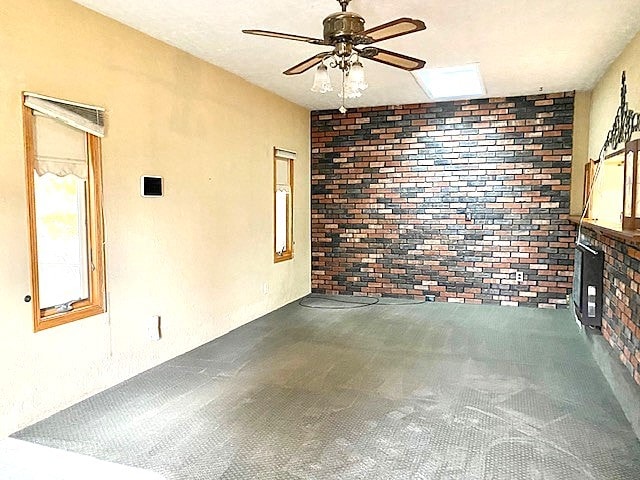 spare room with ceiling fan and brick wall