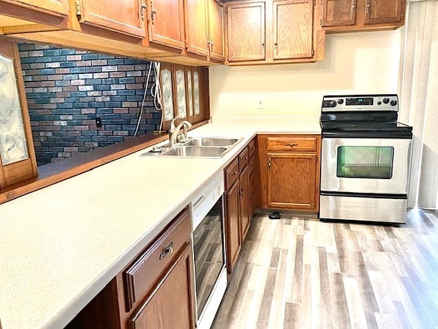 501 Grobe Rd, Sterling, IL 61081 - kitchen featuring appliances with stainless steel finishes, a sink, light wood-style flooring, light countertops, and brown cabinetry