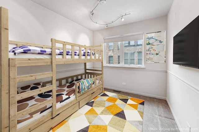 carpeted bedroom featuring a crib and rail lighting