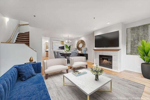 living room featuring light hardwood / wood-style floors, a notable chandelier, and a tiled fireplace