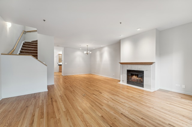 unfurnished living room with a notable chandelier and light hardwood / wood-style floors