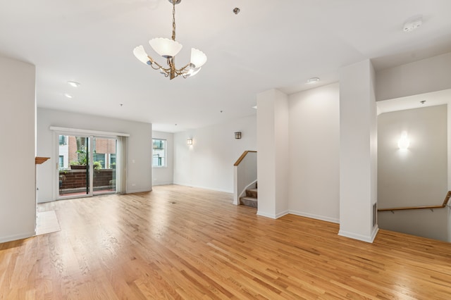 unfurnished living room with light wood-type flooring and an inviting chandelier