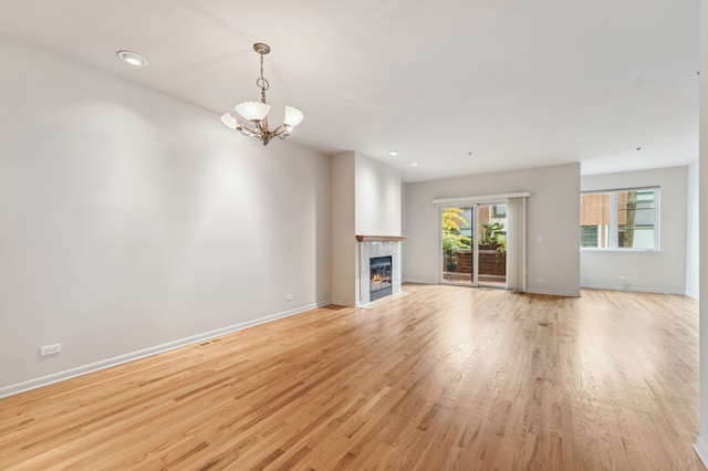 unfurnished living room featuring light wood-type flooring and an inviting chandelier