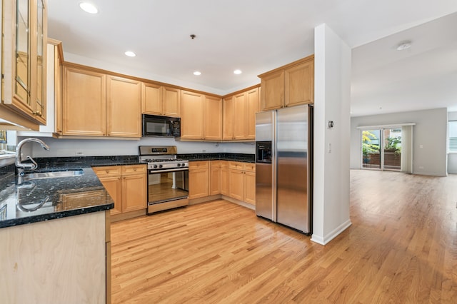 kitchen featuring sink, appliances with stainless steel finishes, light wood-type flooring, and dark stone countertops