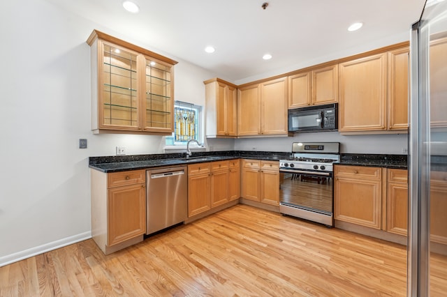 kitchen featuring dark stone countertops, light wood-type flooring, and stainless steel appliances