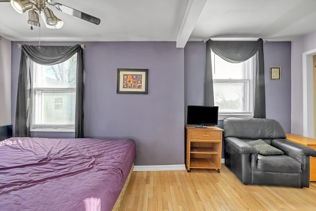 bedroom featuring multiple windows, ceiling fan, beamed ceiling, and light hardwood / wood-style floors