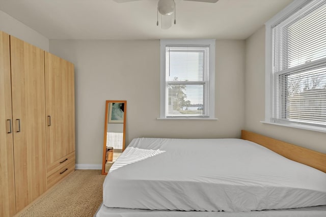 carpeted bedroom featuring multiple windows and ceiling fan