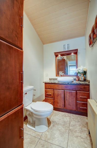 bathroom featuring lofted ceiling, tile patterned floors, toilet, radiator heating unit, and wood ceiling