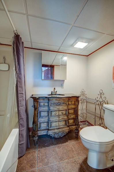 full bathroom featuring a paneled ceiling, vanity, shower / bath combination with curtain, and toilet