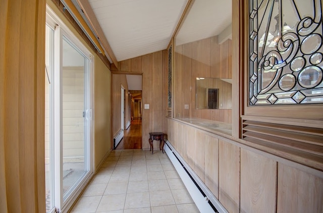 hallway featuring baseboard heating, wood walls, light tile patterned floors, and vaulted ceiling