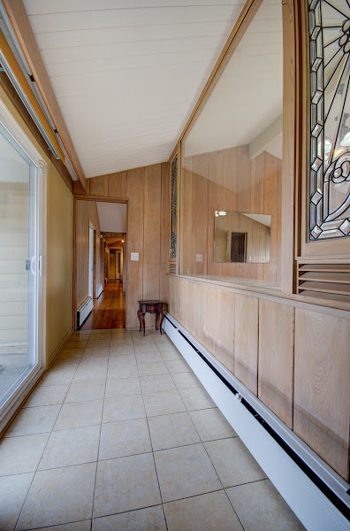 hall featuring vaulted ceiling with beams, light tile patterned floors, and a baseboard radiator