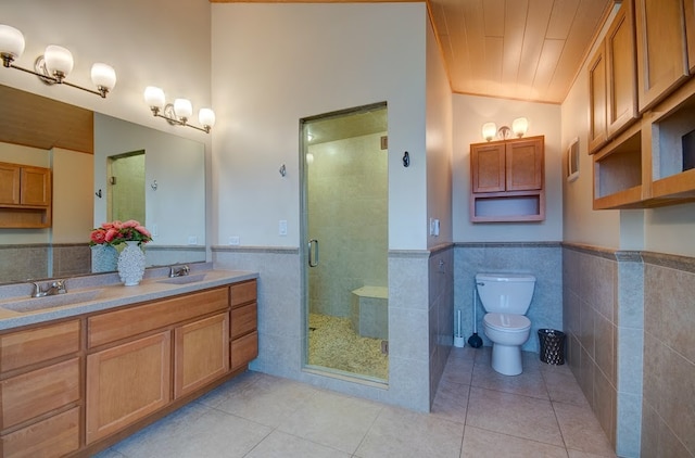 bathroom featuring tile patterned floors, vanity, a shower with shower door, and tile walls