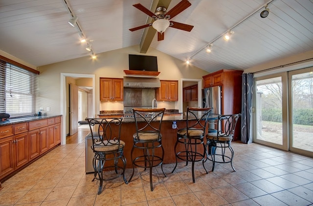 kitchen featuring a kitchen breakfast bar, an island with sink, lofted ceiling, and rail lighting