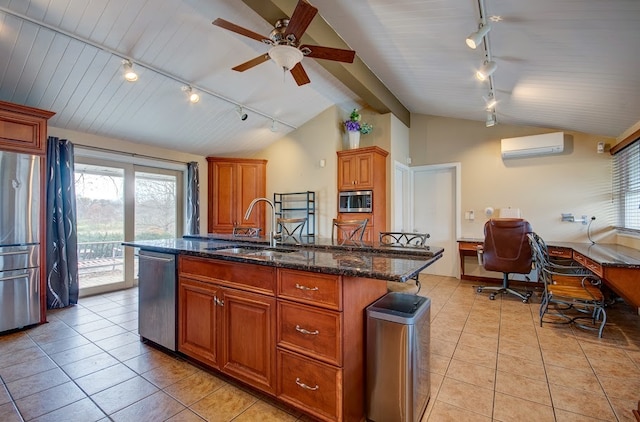 kitchen with a wall mounted air conditioner, lofted ceiling, a center island with sink, sink, and appliances with stainless steel finishes