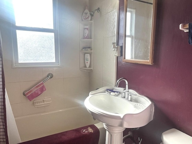 full bathroom featuring sink, tiled shower / bath, and toilet