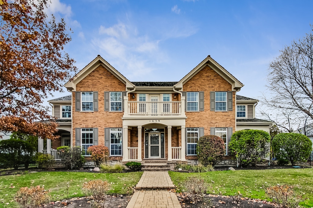 view of front of home with a balcony and a front lawn