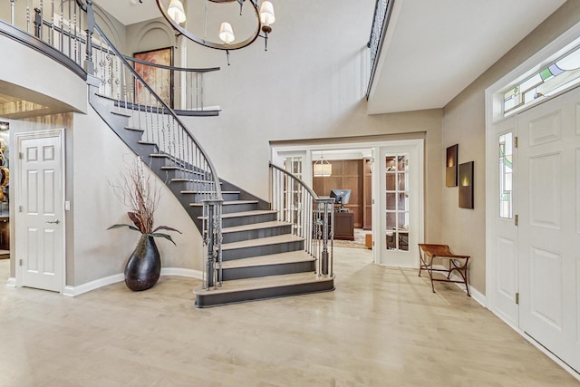 foyer with hardwood / wood-style floors, a towering ceiling, and an inviting chandelier