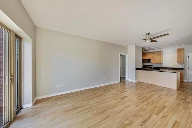 unfurnished living room featuring ceiling fan and light wood-type flooring