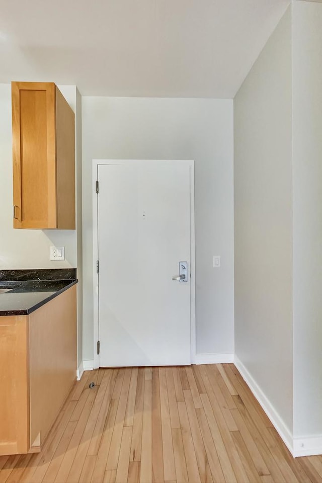 interior space with dark stone countertops and light wood-type flooring