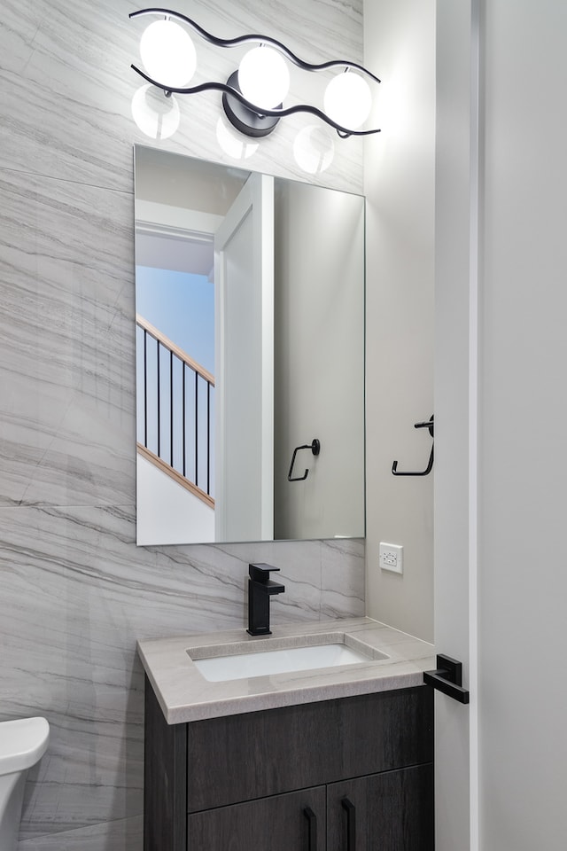 bathroom featuring vanity, toilet, and tile walls