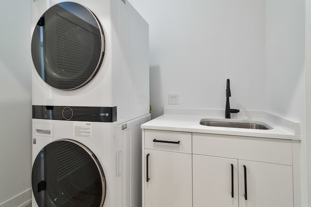 clothes washing area featuring stacked washer and dryer, cabinets, and sink