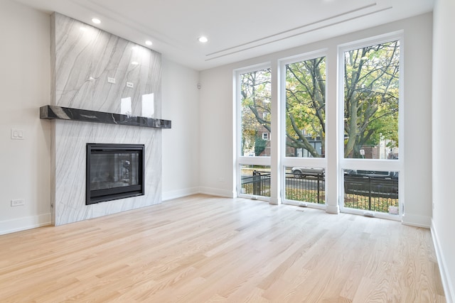 unfurnished living room with a tile fireplace and light hardwood / wood-style flooring