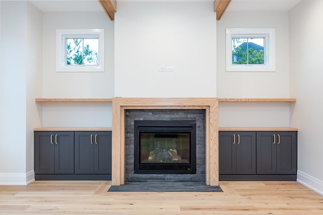 unfurnished living room with beamed ceiling, light wood-type flooring, and plenty of natural light