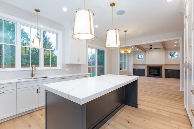 kitchen featuring light hardwood / wood-style floors, white cabinetry, a kitchen island, and sink