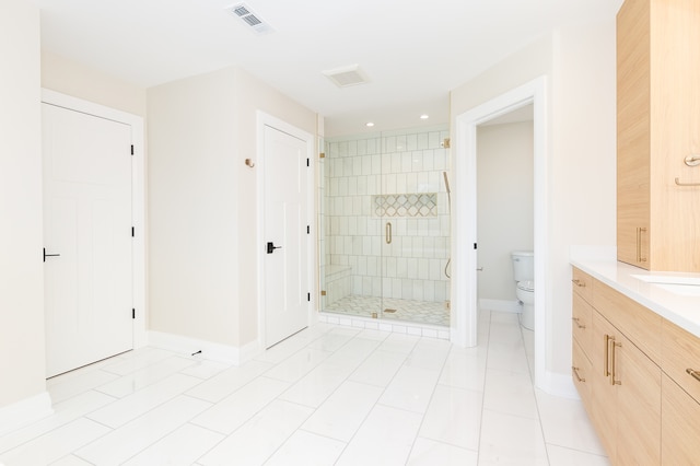 bathroom featuring tile patterned flooring, vanity, toilet, and a shower with door