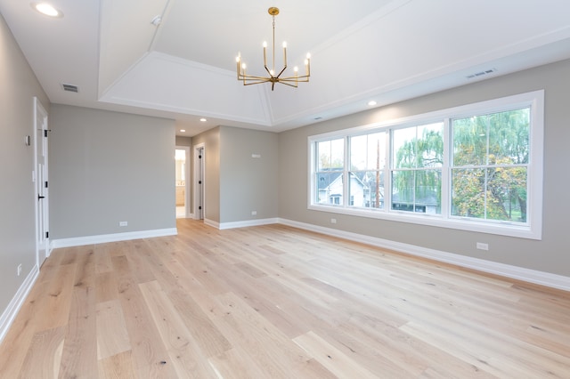 unfurnished room with a chandelier, light wood-type flooring, and a raised ceiling