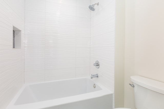 bathroom with toilet and tiled shower / bath