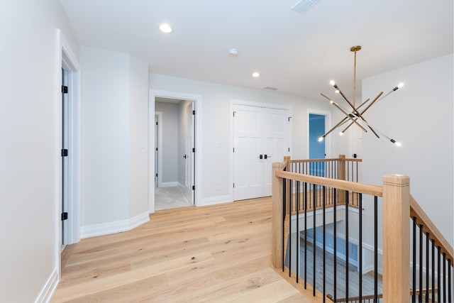 corridor featuring light hardwood / wood-style floors and a chandelier