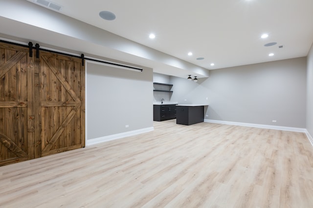 basement featuring a barn door and light hardwood / wood-style floors