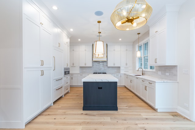 kitchen featuring white cabinetry, a kitchen island, light wood-type flooring, and custom exhaust hood