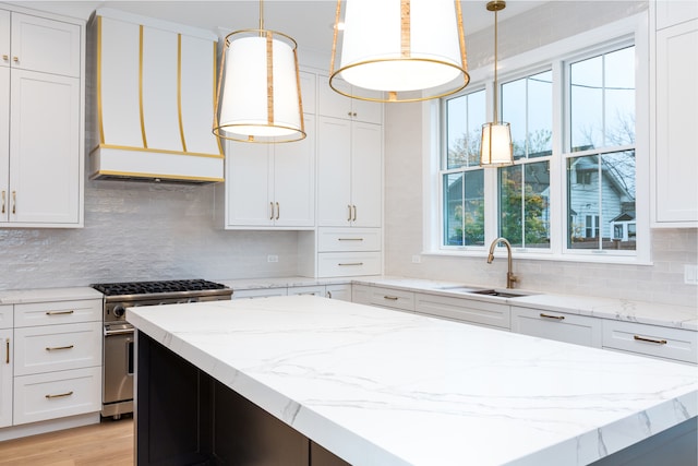 kitchen featuring pendant lighting, white cabinets, high end stove, and sink