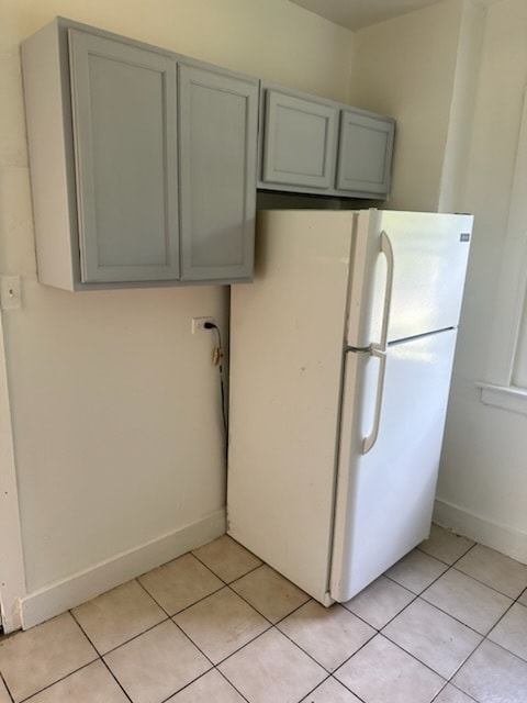 kitchen featuring white refrigerator, gray cabinetry, and light tile patterned flooring