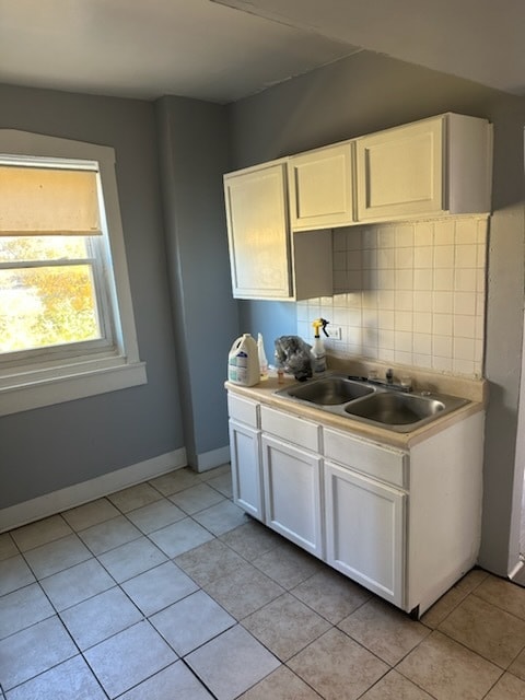 kitchen featuring white cabinets, backsplash, light tile patterned flooring, and sink