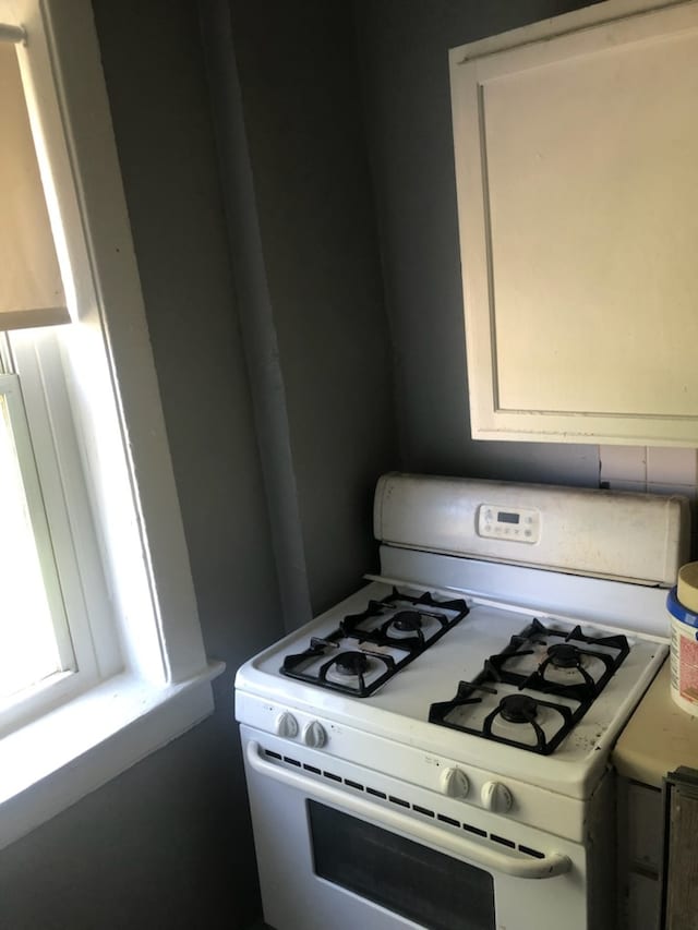 kitchen with white gas range oven and white cabinets